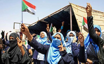 Sudanese women wave national flags as they take